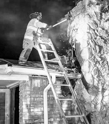 TAKING OUTTHE FLAME - The Levelland Fire Department (LFD) responded to the 1800 block of Houston Street Monday night after receiving a report of a structure fire. Upon arrival, fire was exposed through the roof on the side of the structure. Pictured is an LFD firefighter knocking out a portion of the chimney to expose the flames. (Photo courtesy of the LFD)