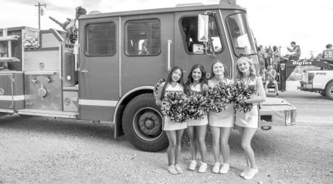 GO SUNDOWN! - Pictured are Sundown Cheerleaders Kaytlin Clausen, Emma Escamilla, Brooklyn Keesler and Sarah Posadas posing in front of a fire truck before walking in the Oil Patch Days Parade on Saturday. (Staff photo by Ada Niederhauser)