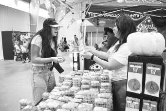 FUN WITH CANDLES - Pictured are Emma Ayers and Angie Garza smelling candles at the Yucca Blossom Trade Day event at the Mallet Event center on Saturday. At the event, vendors had the opportunity to talk with customers while advertising their business and possibly having some sales. (Staff photo by Ada Niederhauser)