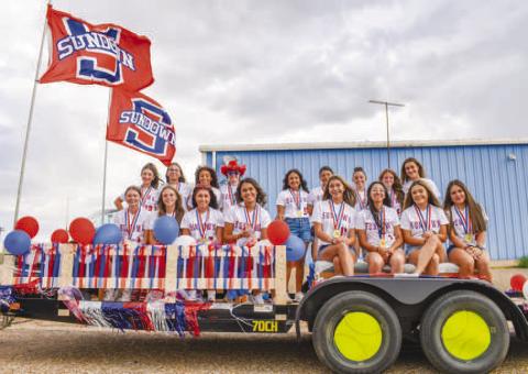 SOFTBALL FLOAT – The wind was perfect to catch the flags on the Sundown Softball team’s float for the Oil Patch Days Parade on Saturday. Players could be seen wearing gold medals from their win at state earlier this year. (Staff photo by Ada Niederhauser)