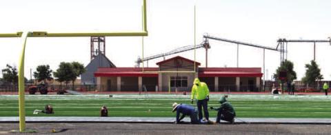EDGES SECURED - Contractors secure the edge of the new artificial turf field at Levelland High School. (Staff photo by Trinity Bourdeaux)