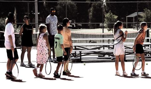 CAMPERS ON DECK- Young tennis players wait in line for their turn during a target-hitting drill at summer tennis camp. The multi-day camp gave local youth kids a chance to build athletic skills and stay active over the summer break.
