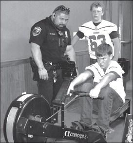 One of the booths at the Exploration Event at the Mallet Event Center on Thursday was Officer R. Nino teaching and timing Cody Holdman one of the students participation in the event as he tried to break a record on a Concept 2 training equipment while Aiden Brinklow cheered him on. (Staff photo by Emily Campos)