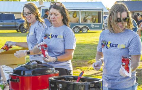 BLUE &amp; YOU VOLUNTEERS - Pictured from left to right are: Andrea Corley, Megan Tyler and Amber Smith taking part in Texas Night Out as Blue &amp; You volunteers. Walking Tacos were the food of choice for the event at Kauffman Park last Tuesday evening. (Staff photo by Evin Thomas)
