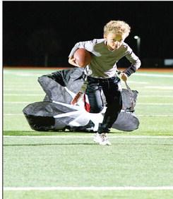 PARACHUTE RUN - Kyler Dent carries the football while dragging a resistance training parachute with him at Lobo Stadium this past Monday. Dent is a part of the 8u Levelland Lobos flag football team that will be competing at the Star in Frisco for an NFL Regional Flag Football tournament over the weekend. (Staff photo by Jentezen Smith)