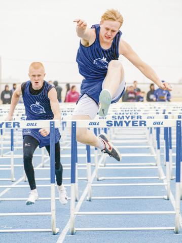 BOBCAT HURDLERS - Smyer’s Alex Mattox clears a hurdle while his teammate James Rampy prepares to do the same behind him this past Friday at the Bobcat Relays at Smyer High School. (Staff photo by Eric Venkatesan)