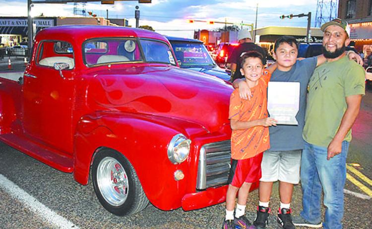 1953 CHOP TOP– Brandon Orosco and his sons, Jacob and Landon, all of Levelland, were having a blast cruising in their red flamed 1953 GMC Chop Top truck Friday night in the Thunder on the Plains Poker Run and Cruise. Orosco’s cousin painted the flames on the classic truck. The truck received a People’s Choice award in the cruise. (Staff Photo)